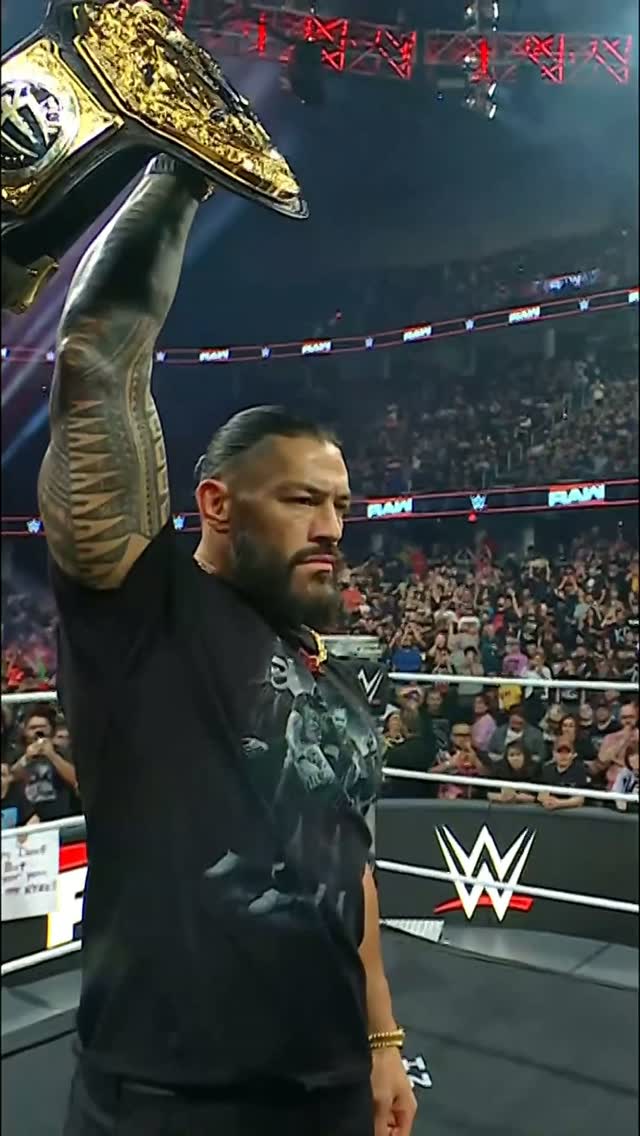 Roman Reigns holds up a WWE Champio...