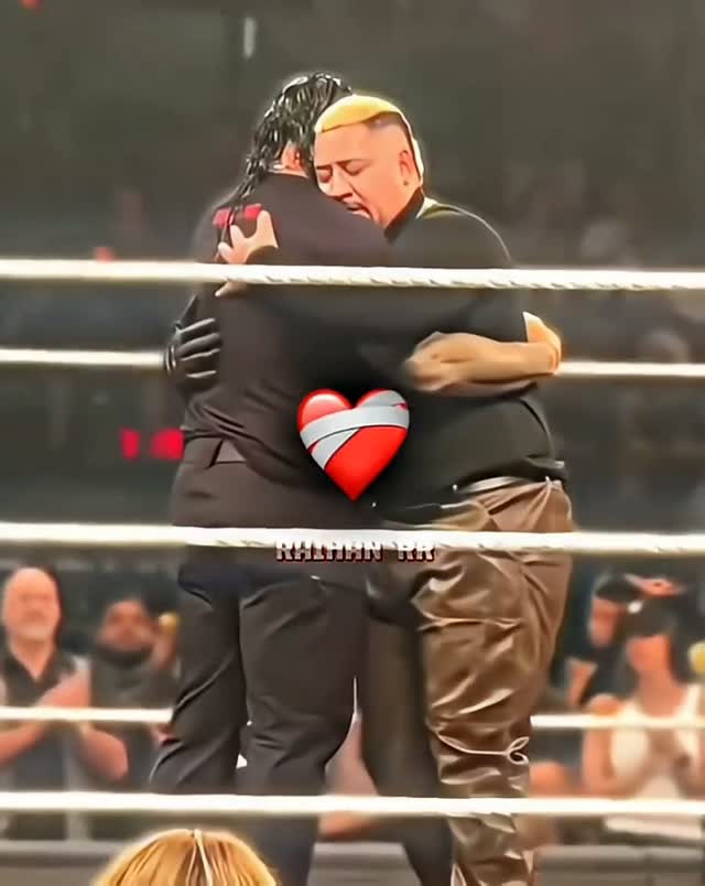 Two wrestlers hug in the ring, over...