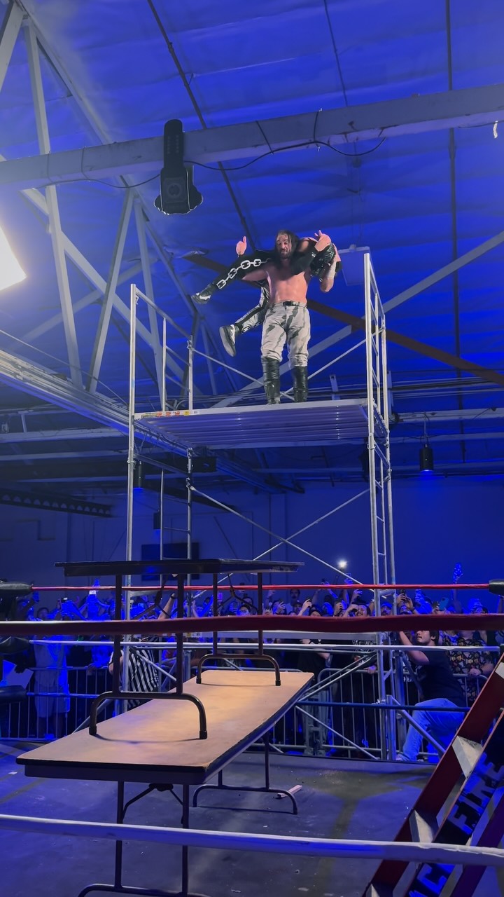 Wrestlers on scaffolding above a ta...